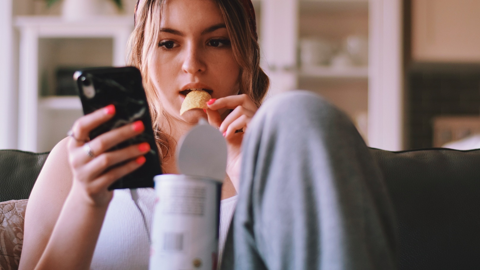 young-teenage-girl-sitting-on-a-couch-eating-pota-2021-09-02-19-55-58-utc